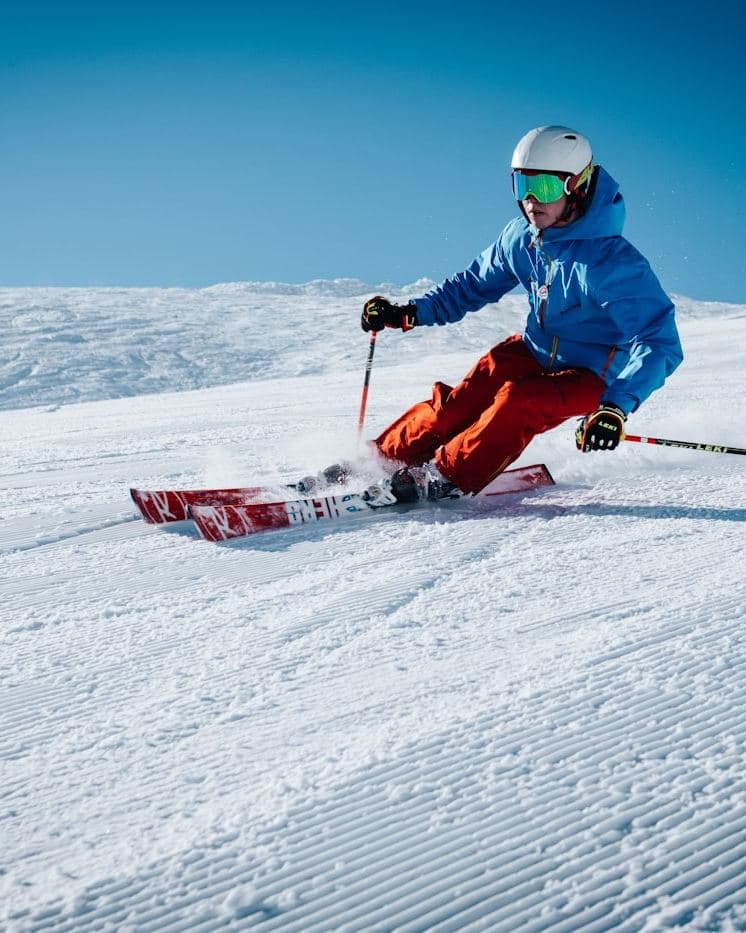 Esquiador trazando una curva en una pista con nieve pisada